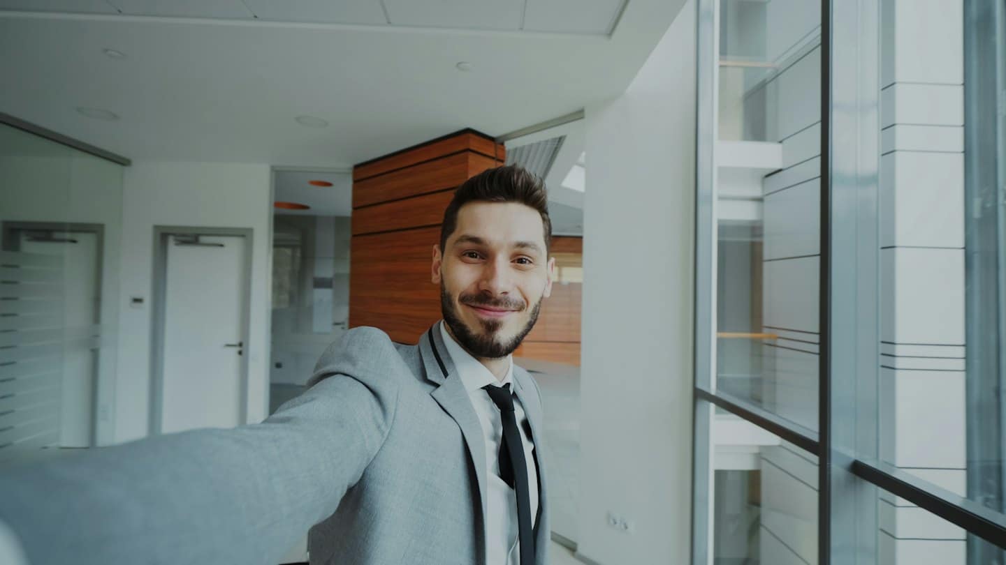 Junger Geschäftsmann macht ein Selfie in einem modernen Büro.